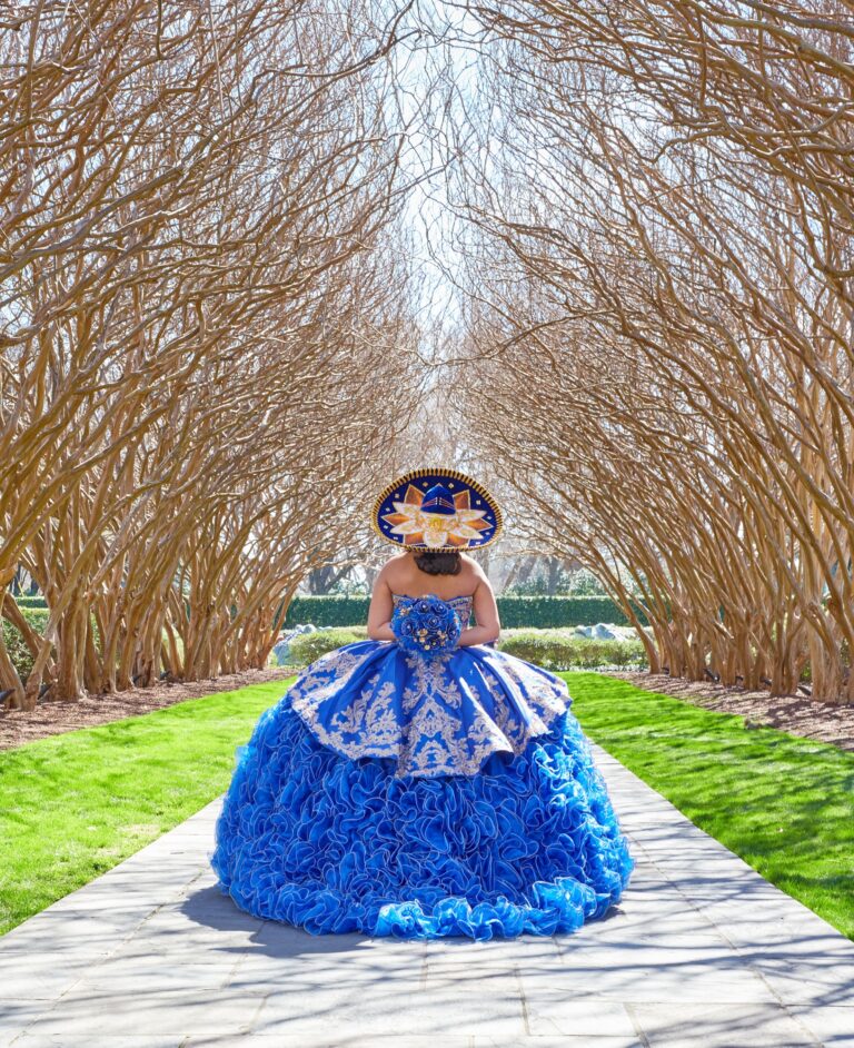 Vertical shot of a female posing in a forest in a blue Quinceanera Dress